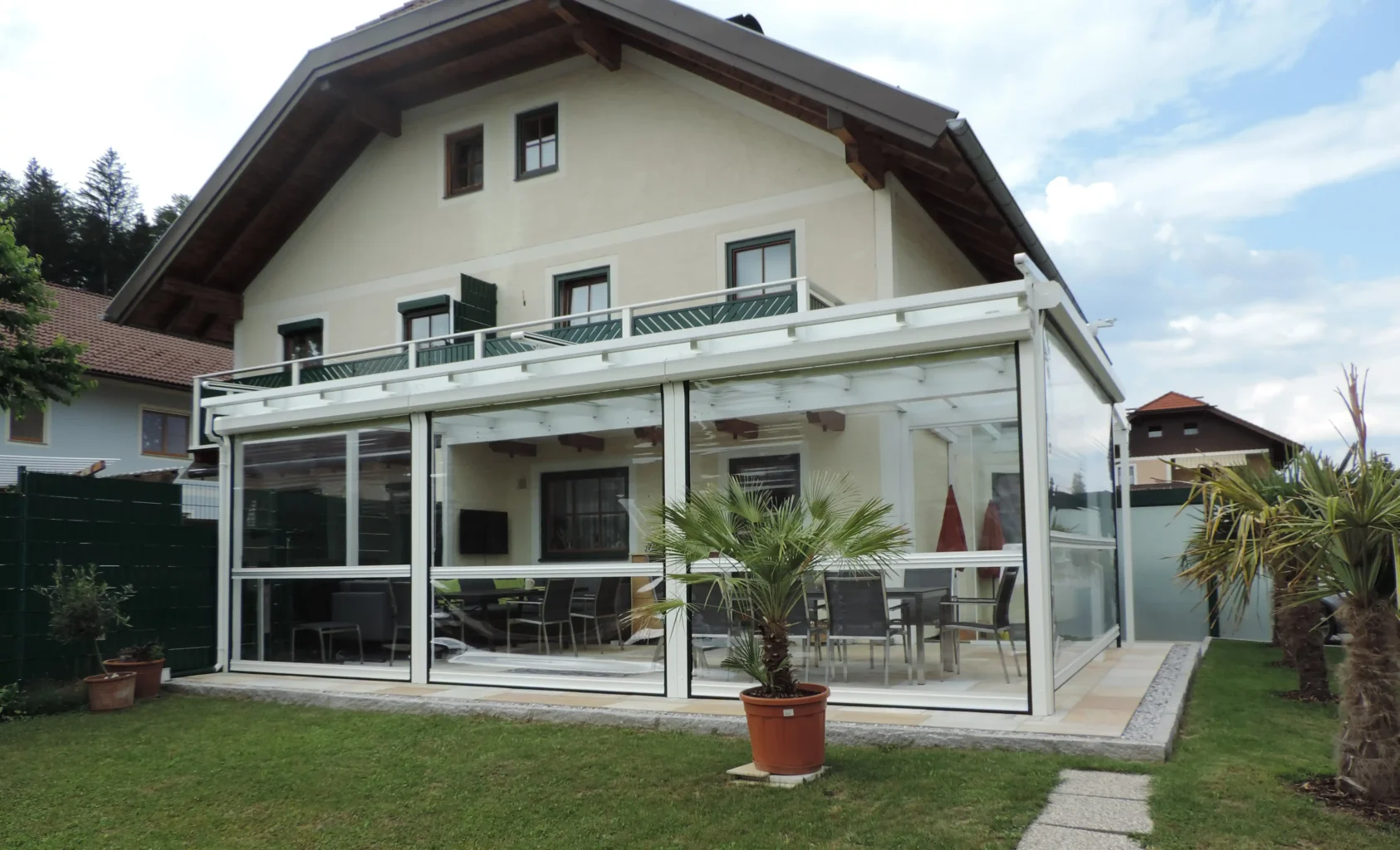 An Hausecke angrenzender Wintergarten mit Rollfenstern an den Seiten