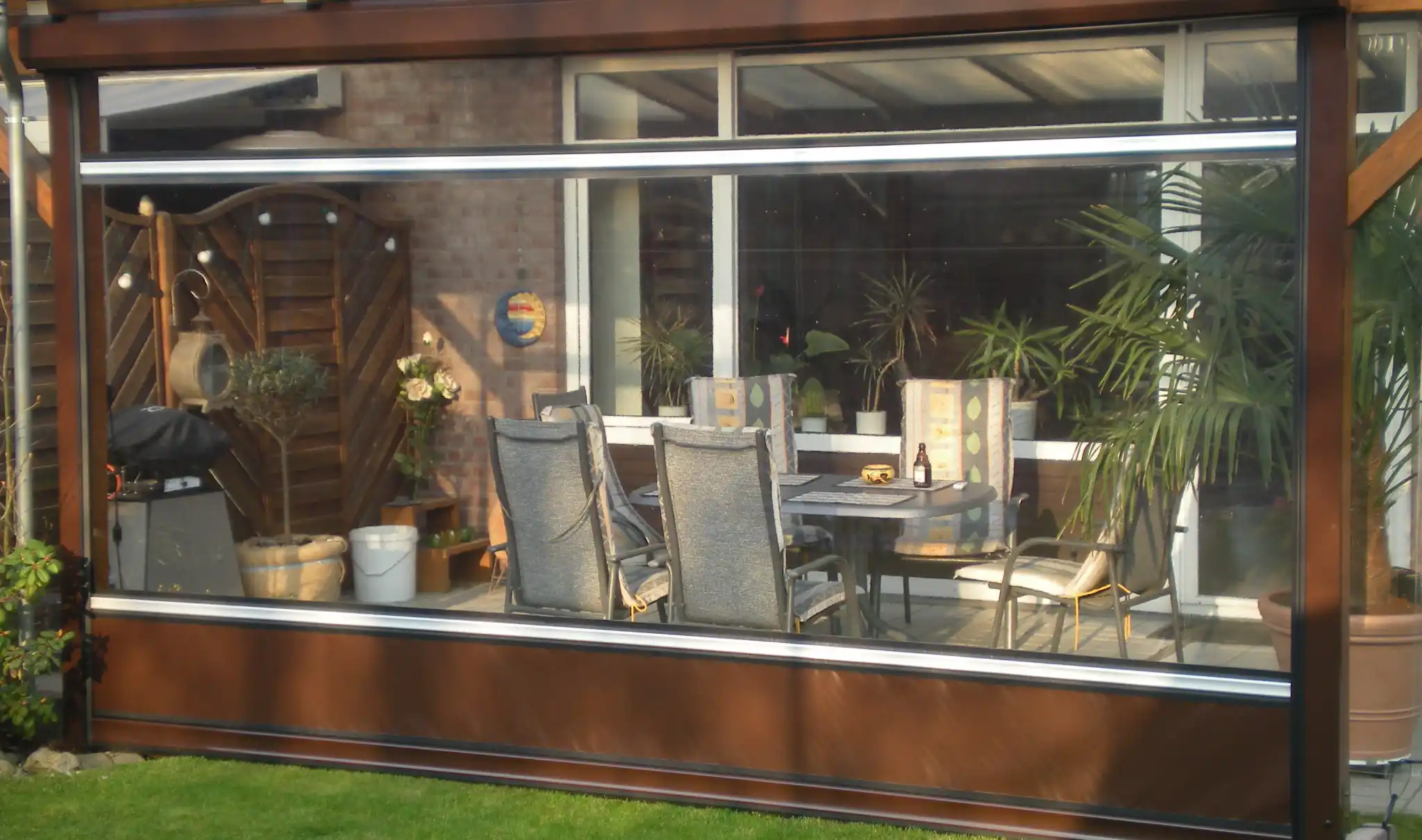 Terrasse mit Sitzgelegenheiten und braunem Rollfenster